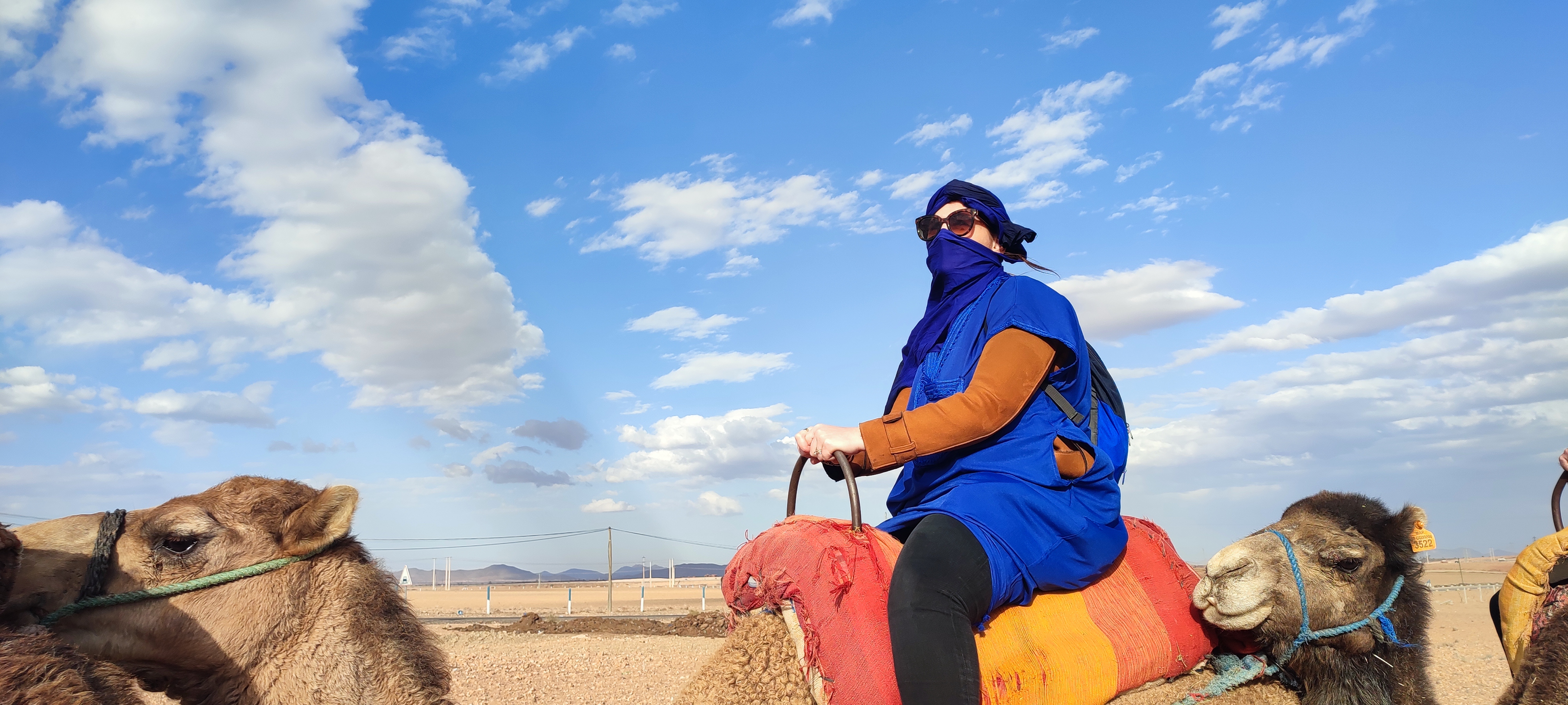 Person in traditional blue Berber clothing riding camel