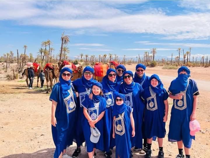 Large group in traditional blue Berber clothing with camels