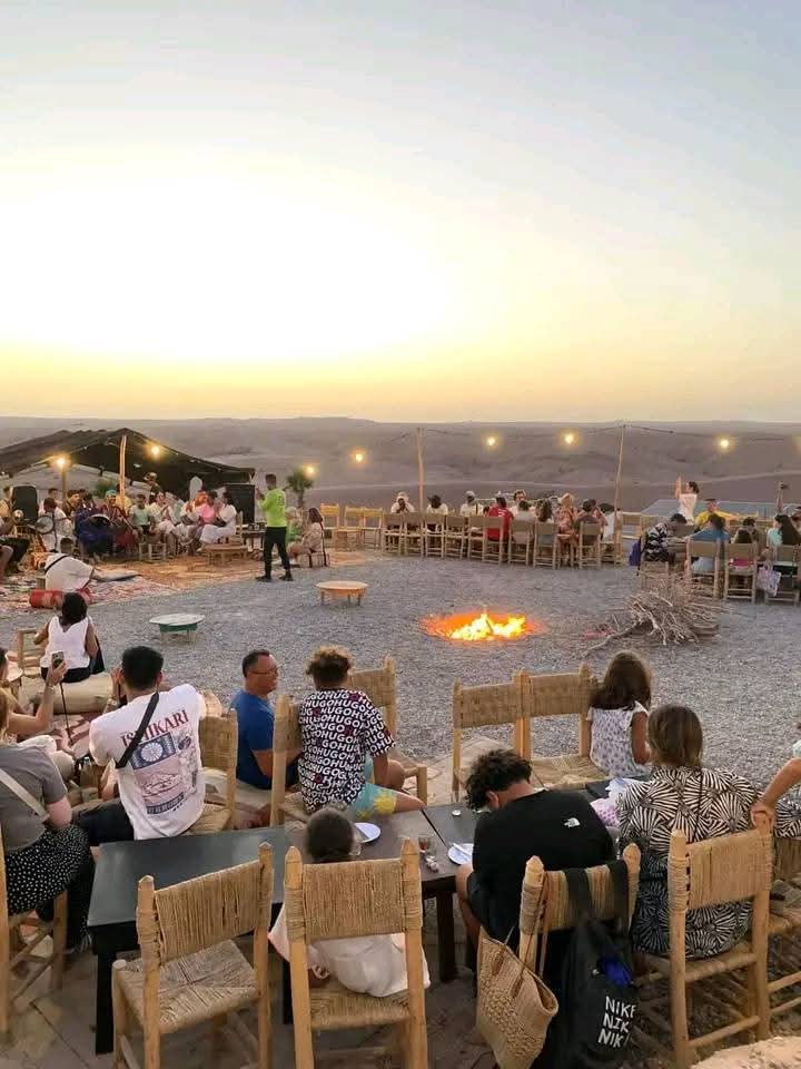 Desert camp with fire and dining setup at sunset