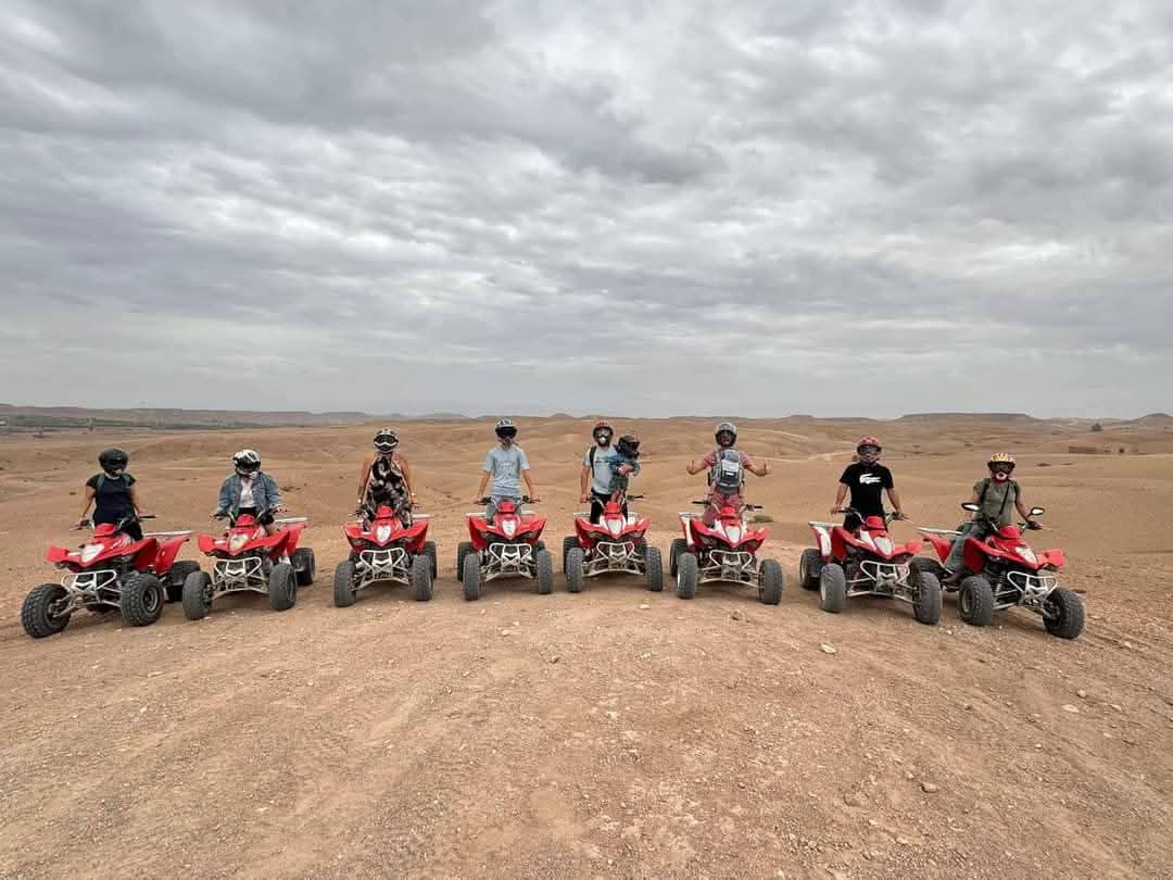 Group of eight riders lined up on red quad bikes