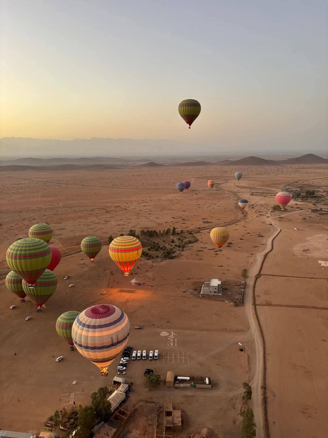 Aerial view of colorful hot air balloons over desert landscape