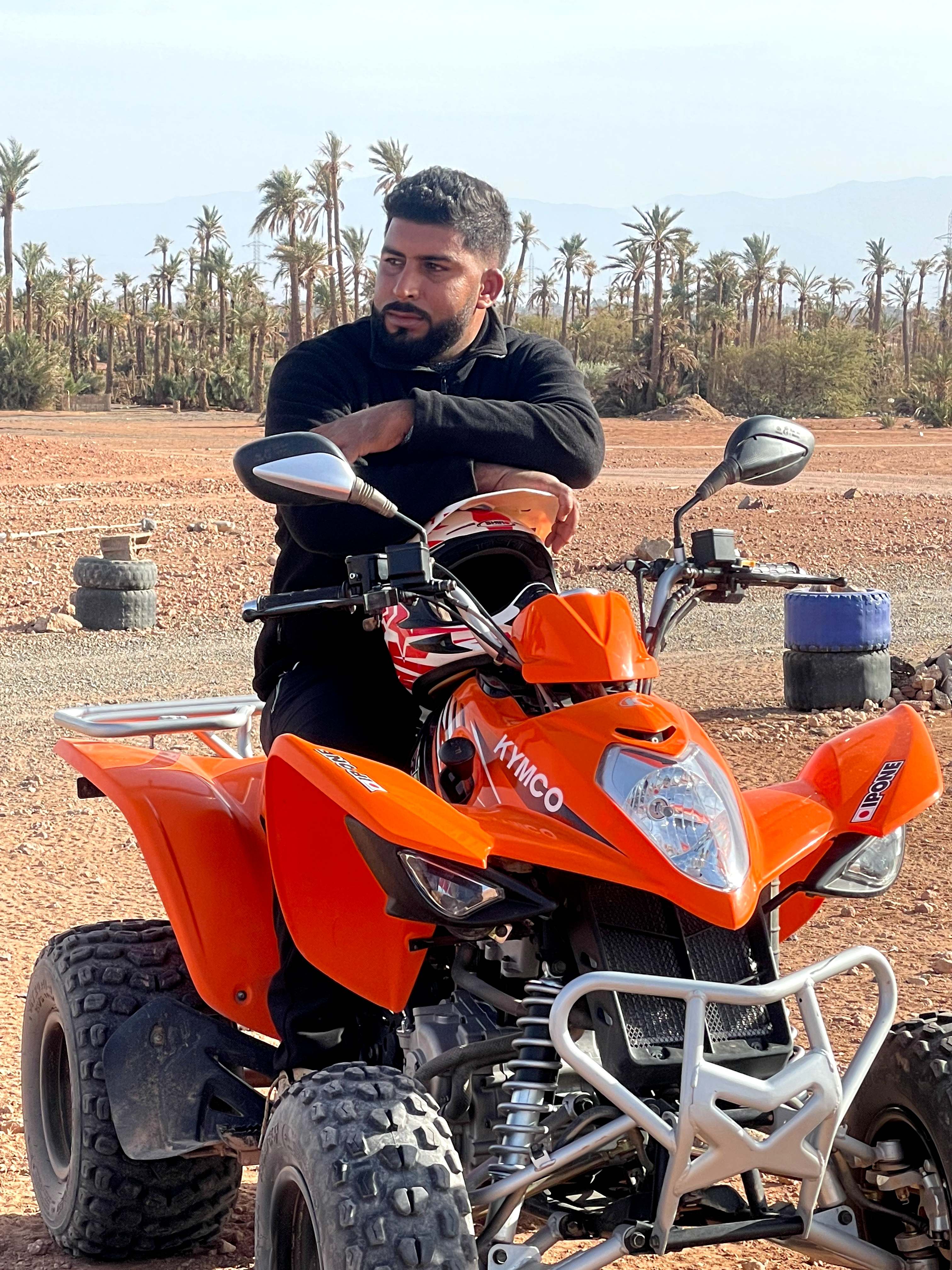 Man sitting relaxed on orange ATV among palm trees