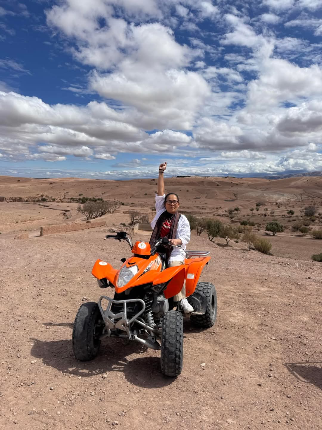 Person celebrating on orange quad bike in desert