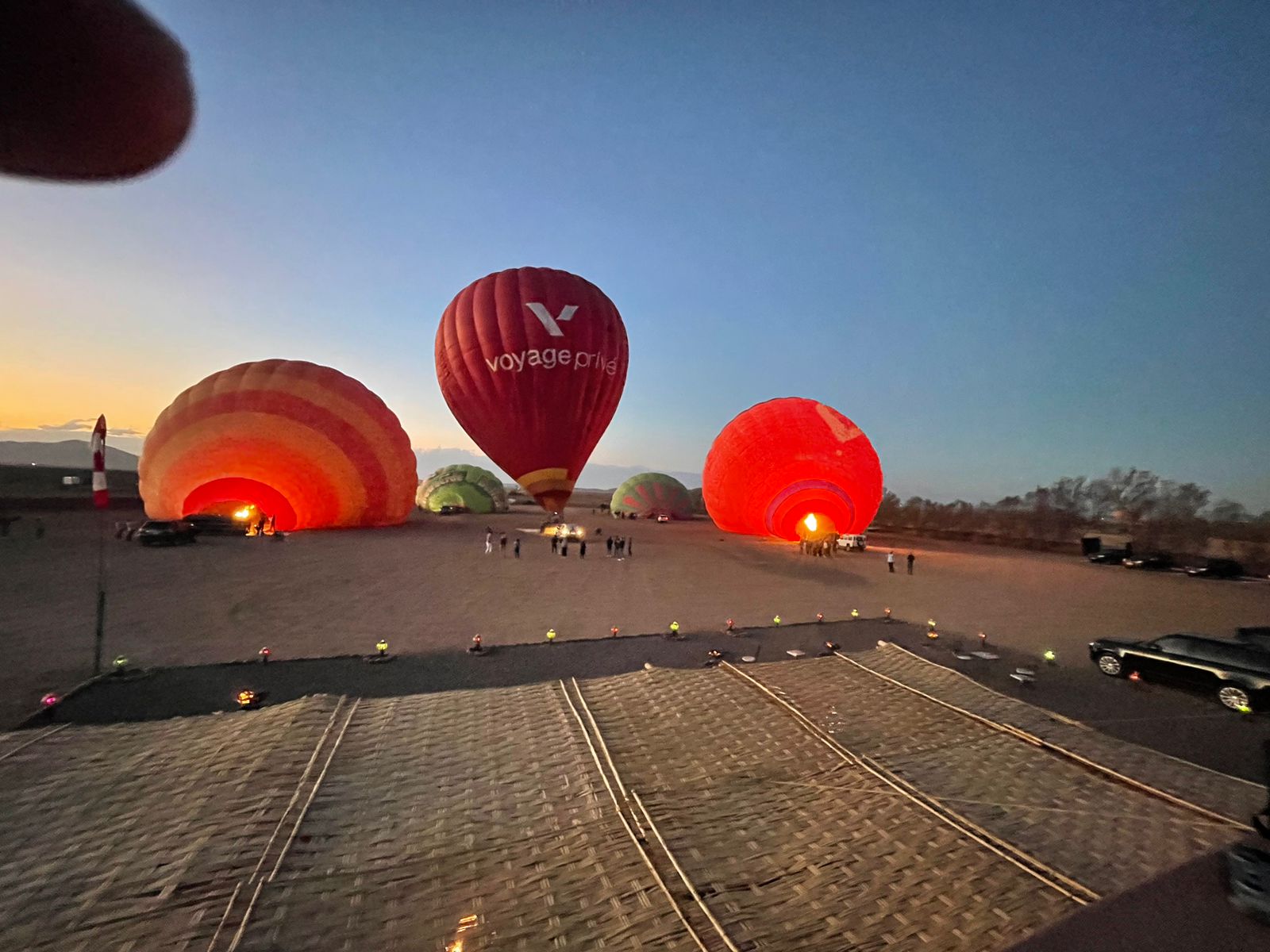 Hot air balloons being prepared at dusk with Voyage Prive branding