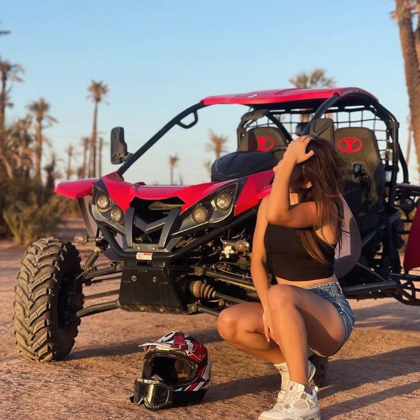 Woman posing next to red buggy among palm trees at sunset