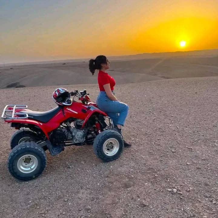 Woman on red quad bike at desert sunset