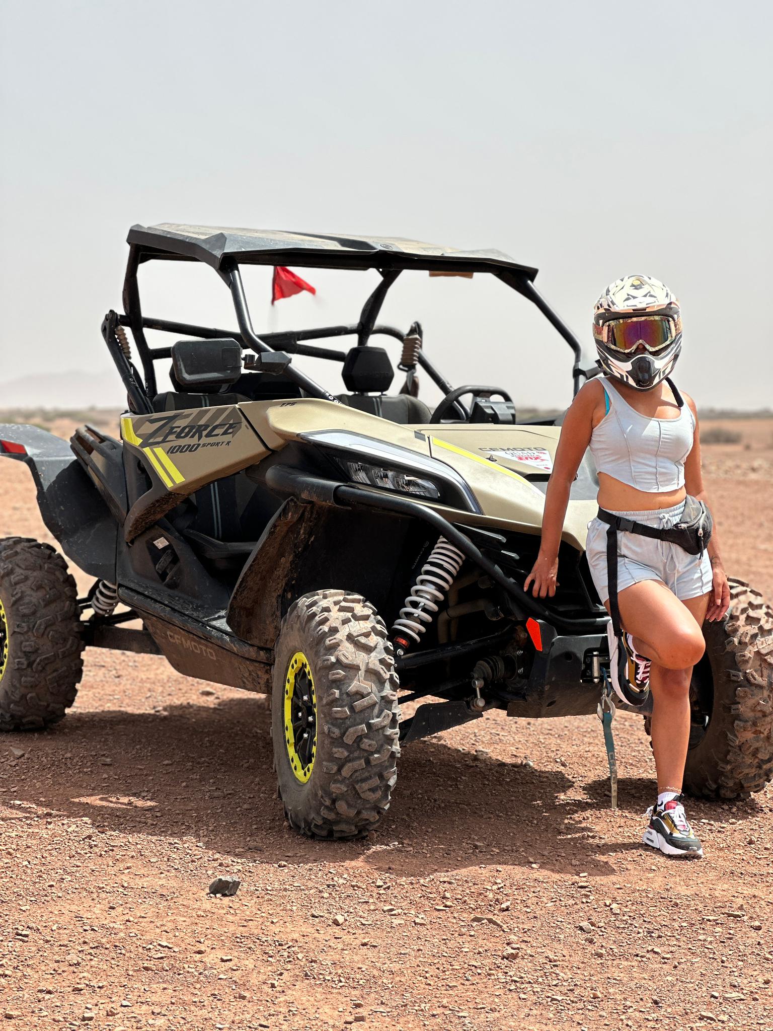 Woman in full gear standing next to yellow and black UTV
