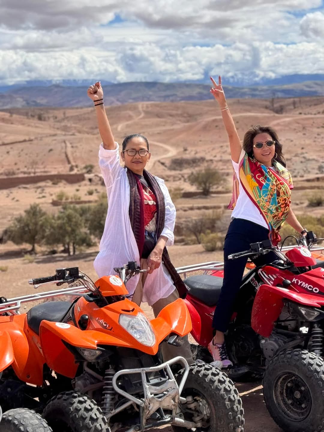 Two women celebrating on quad bikes in desert