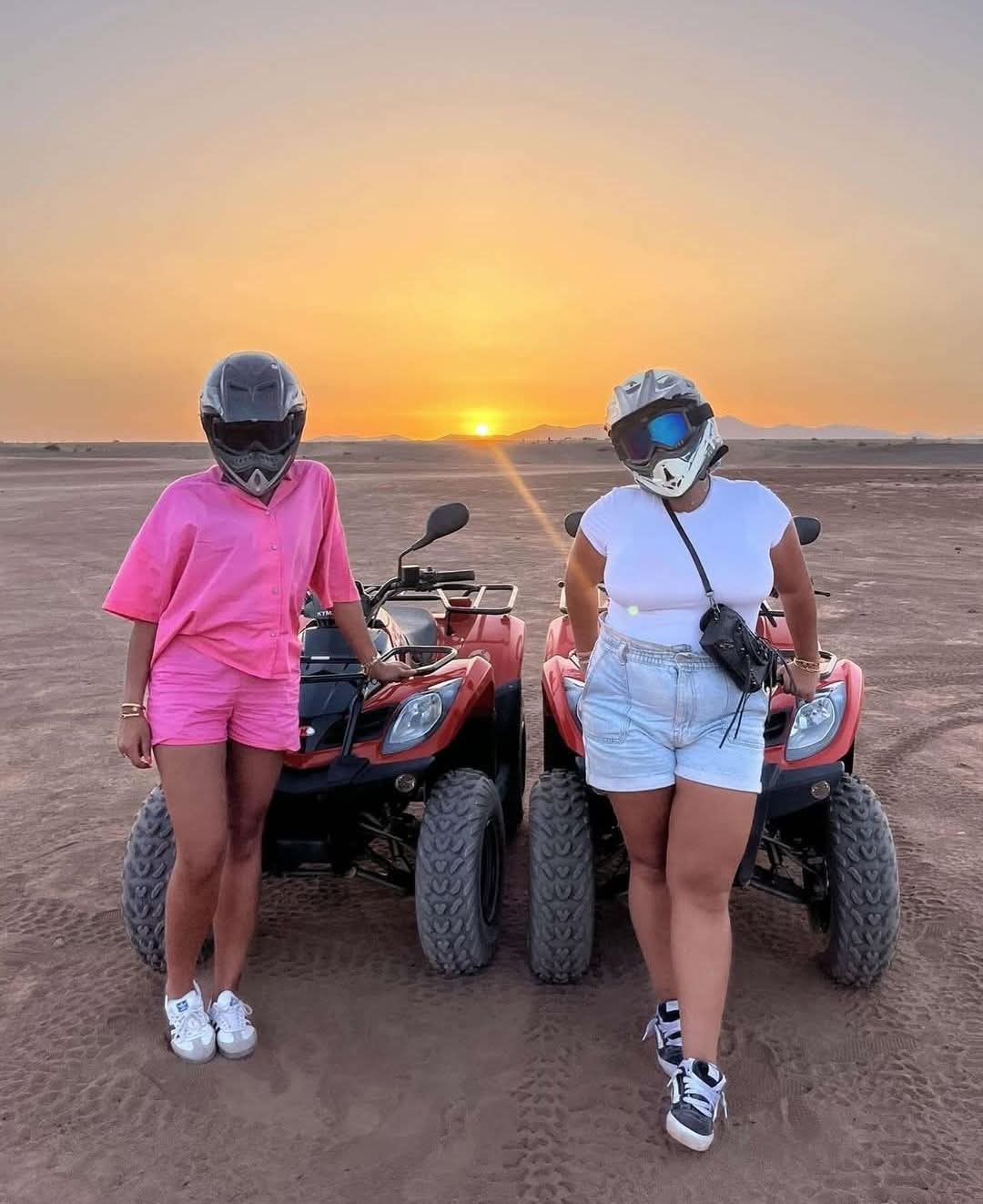 Two women with helmets and quad bikes at sunset